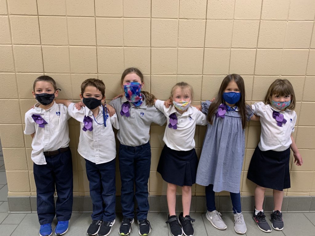 Children Montgomery Catholic military families stand in a line wearing purple to support our military